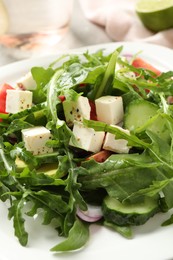 Photo of Delicious salad with feta cheese, arugula and vegetables on plate, closeup