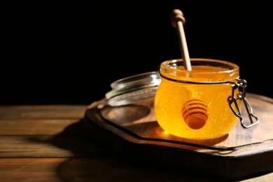 Photo of Fresh honey in jar on wooden table. Space for text