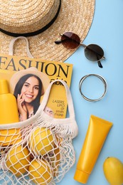 Photo of String bag with magazine, lemons and summer accessories on light blue background, flat lay