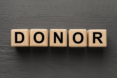 Cubes with word Donor on grey wooden table, top view