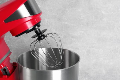 Photo of Modern red stand mixer on light gray background, closeup. Space for text