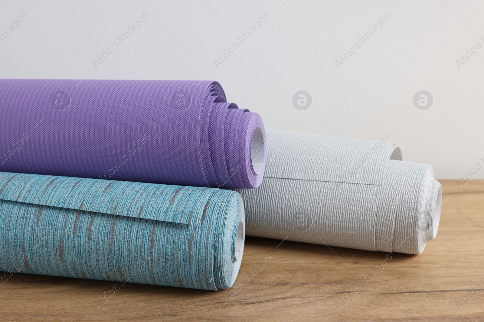 Photo of Three different wallpaper rolls on wooden table