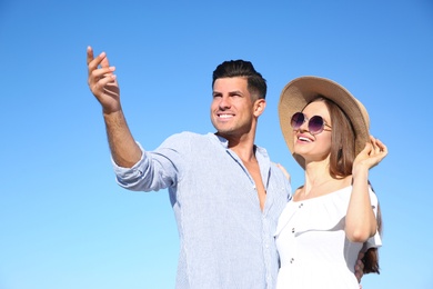 Lovely couple against blue sky outdoors. Summer vacation