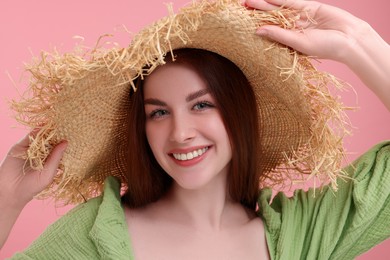 Photo of Portrait of beautiful woman with freckles in straw hat on pink background