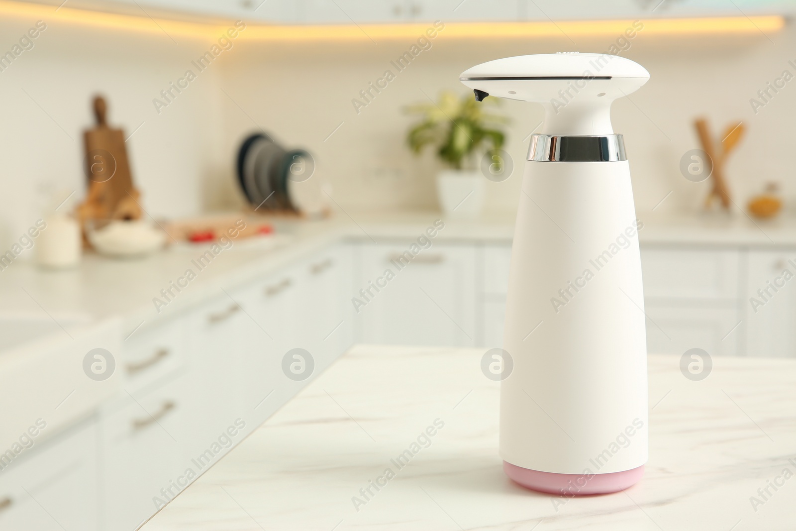 Photo of Modern automatic soap dispenser on countertop in kitchen. Space for text