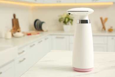 Modern automatic soap dispenser on countertop in kitchen. Space for text
