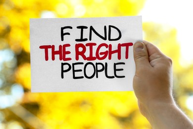 Photo of Man holding card with phrase Find The Right People against blurred background, closeup