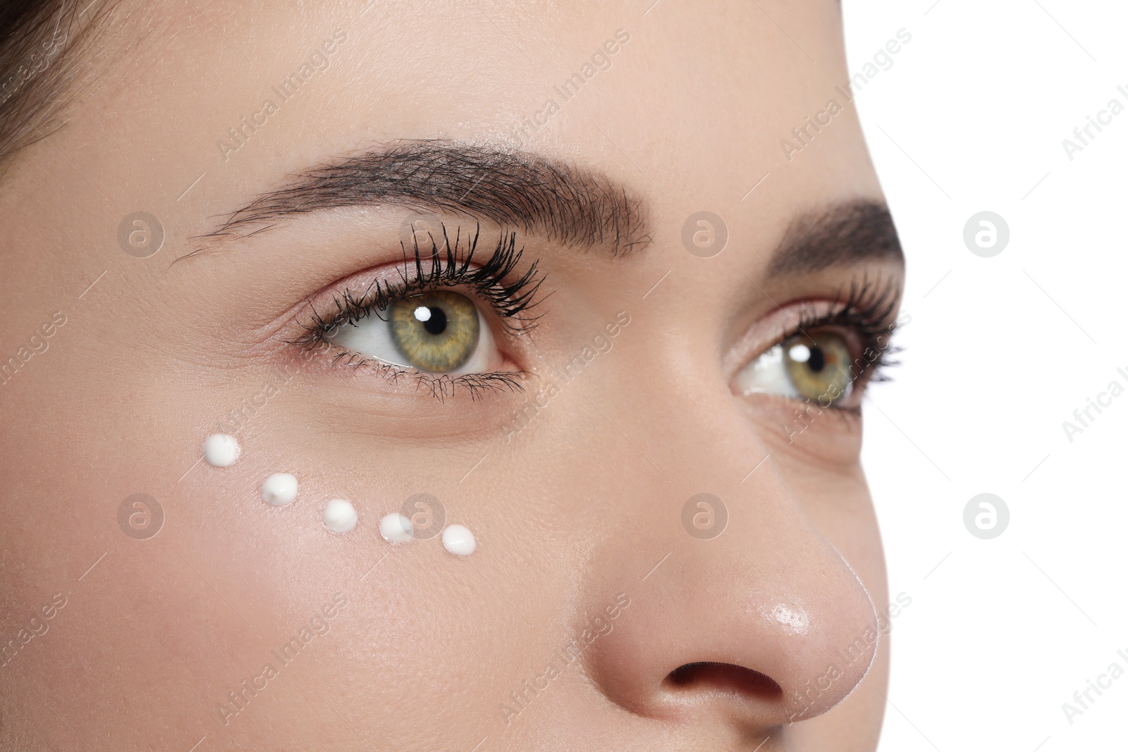 Photo of Young woman with cream around eye on white background, closeup