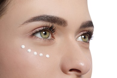 Photo of Young woman with cream around eye on white background, closeup