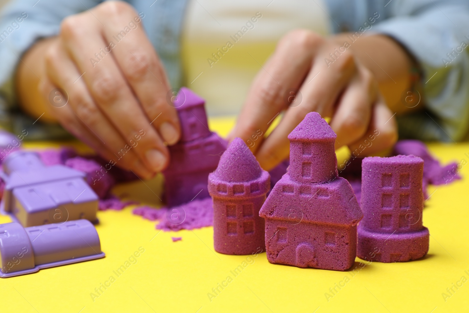 Photo of Woman playing with kinetic sand at yellow table, selective focus