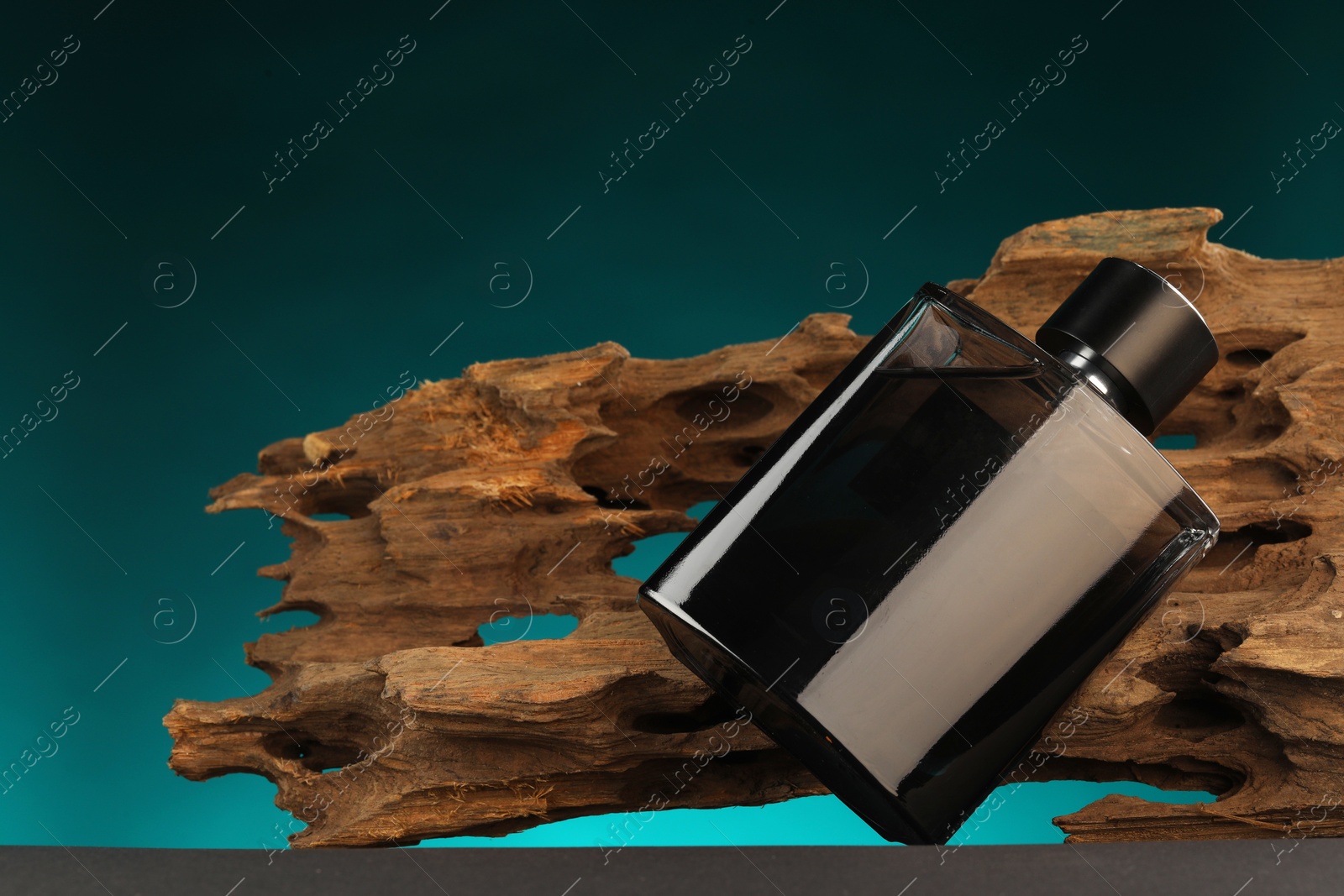 Photo of Luxury men`s perfume in bottle on grey table against color background, space for text