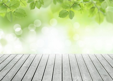 Empty wooden surface and beautiful green leaves on blurred background. Bokeh effect