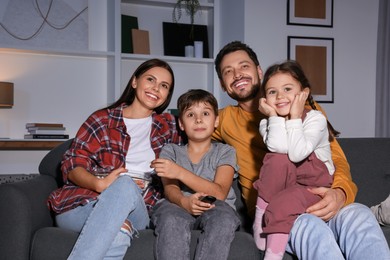Photo of Happy family watching TV at home in evening