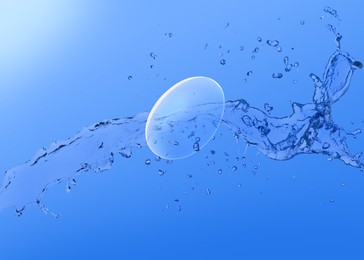 Contact lens and splash of solution on blue background