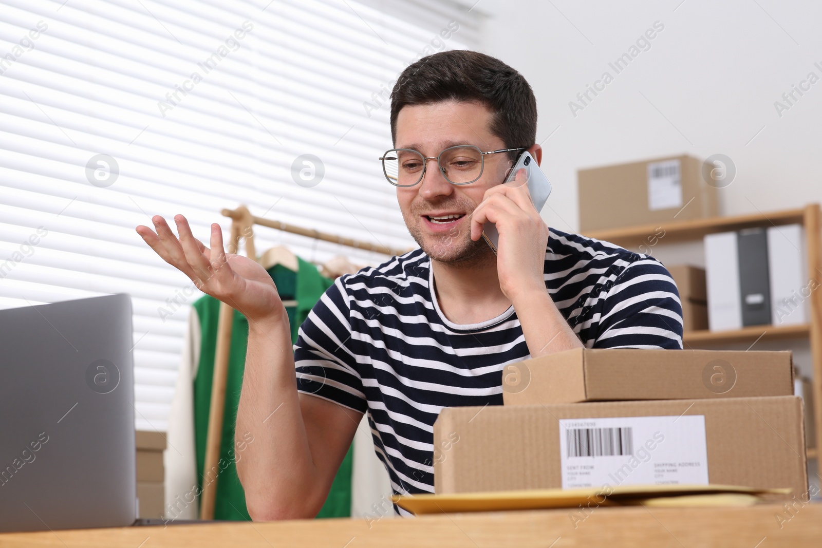 Photo of Seller talking on phone while working in office. Online store