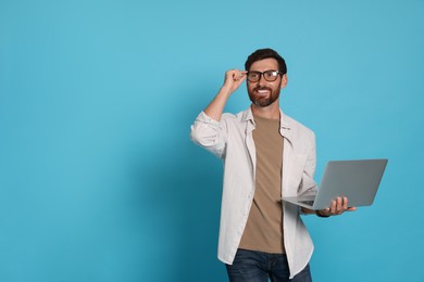 Photo of Handsome man with laptop on light blue background