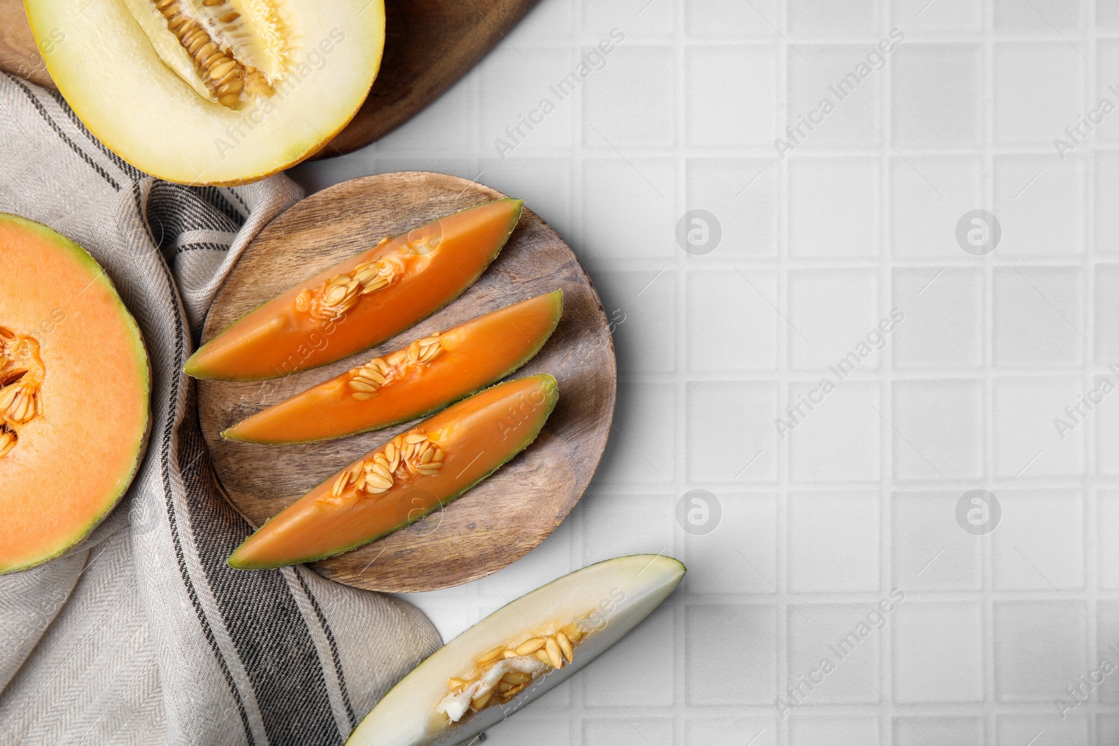 Photo of Tasty ripe melons on white checkered table, flat lay. Space for text