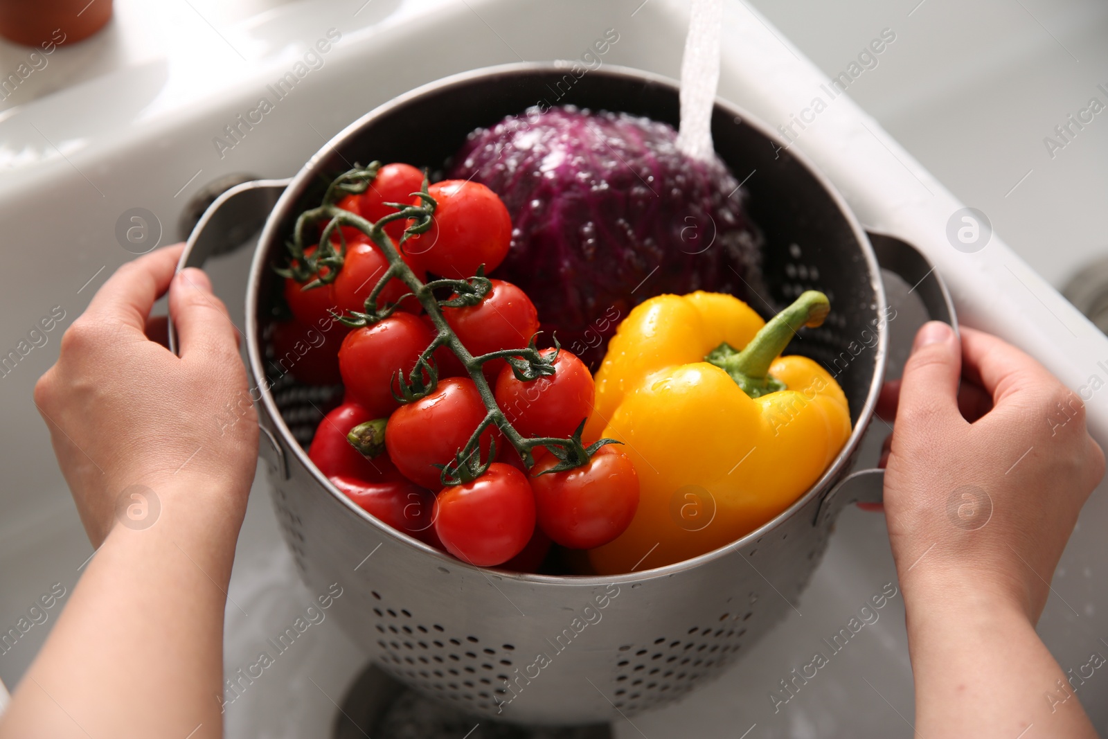 Photo of Woman washing fresh vegetables in kitchen sink, closeup