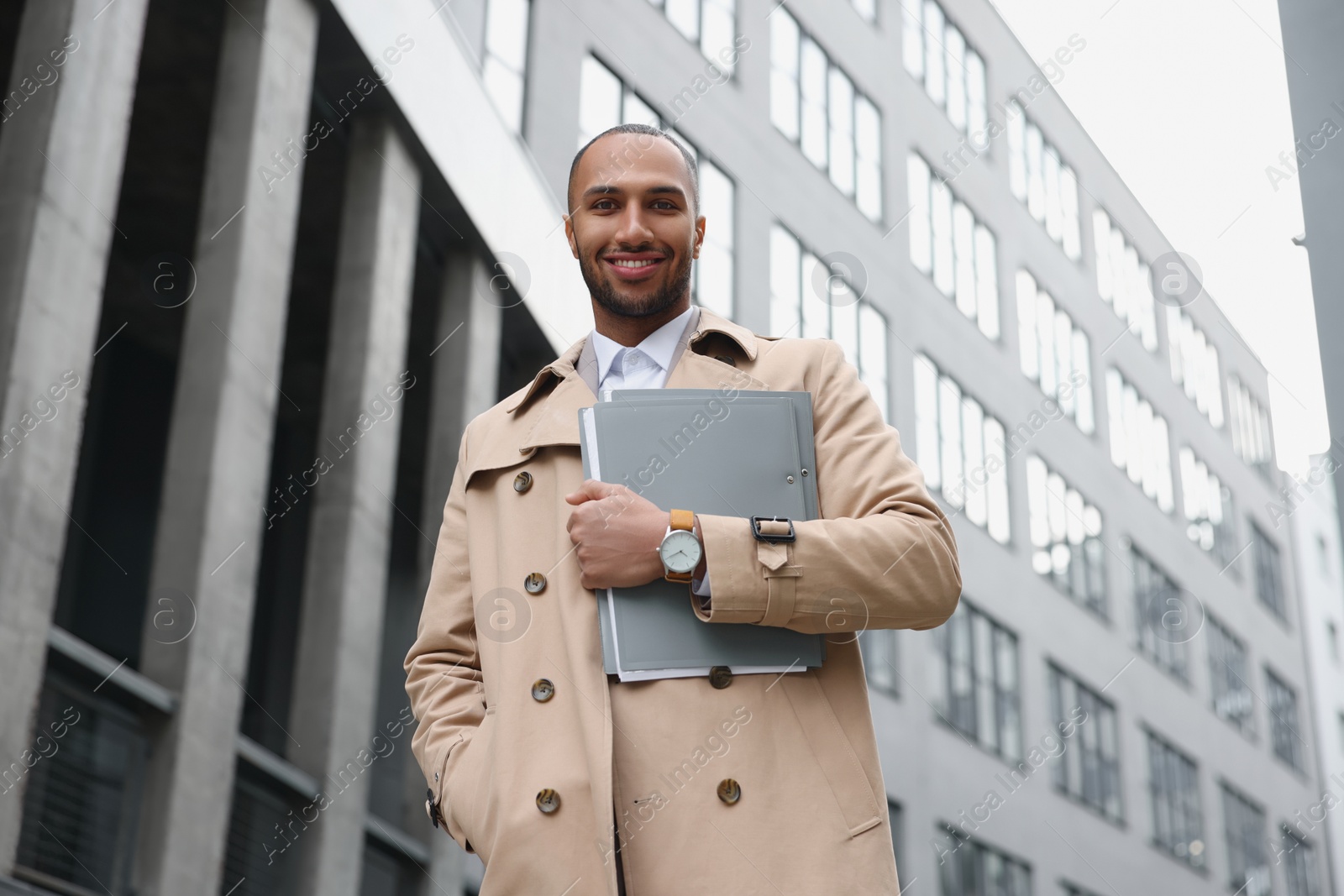 Photo of Happy man with folders outdoors, low angle view. Lawyer, businessman, accountant or manager