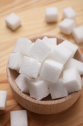 White sugar cubes in bowl on wooden table, above view