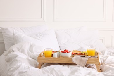 Photo of Good morning. Tray with tasty breakfast on bed at home. Space for text