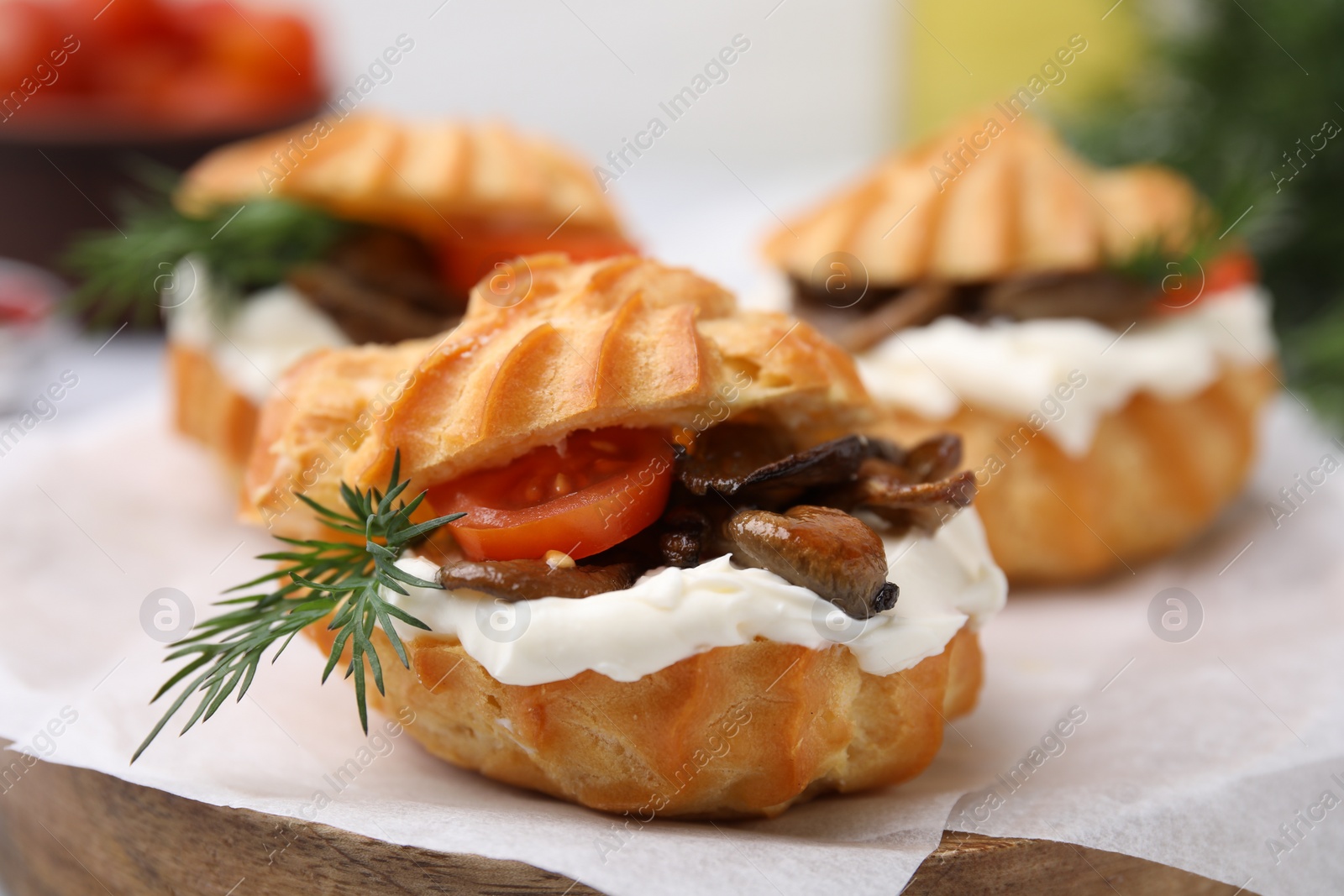 Photo of Delicious profiteroles with cream cheese, mushrooms, tomato and dill on board, closeup