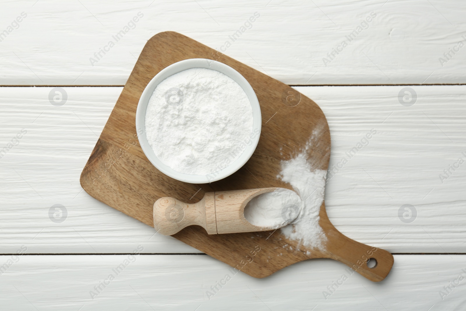 Photo of Baking powder in bowl and scoop on white wooden table, top view