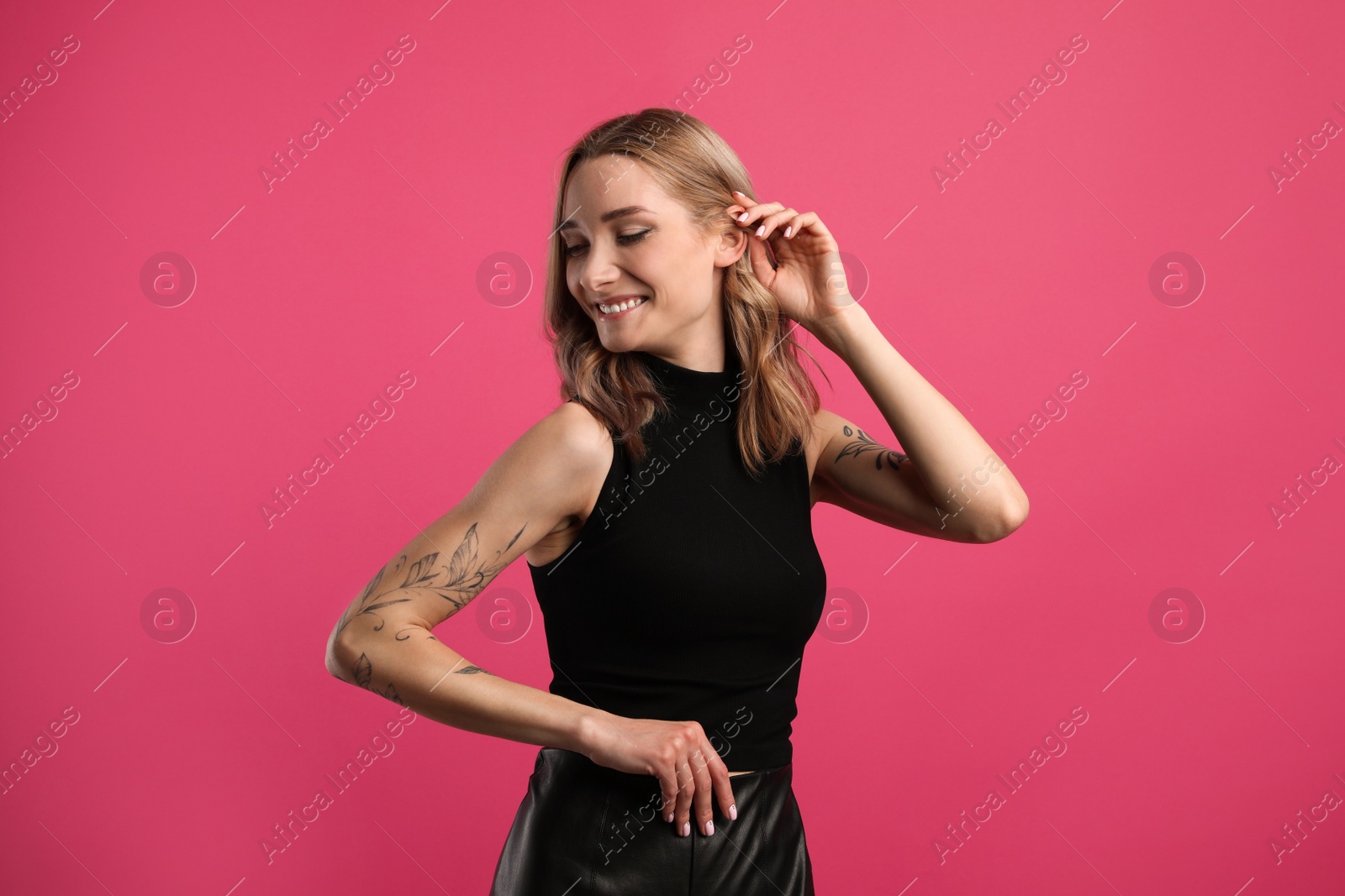 Photo of Beautiful woman with tattoos on arms against pink background