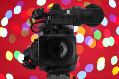 Photo of Modern video camera against blurred colorful lights