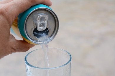 Photo of Woman pouring drink from aluminum can into glass on blurred background, closeup. Space for text