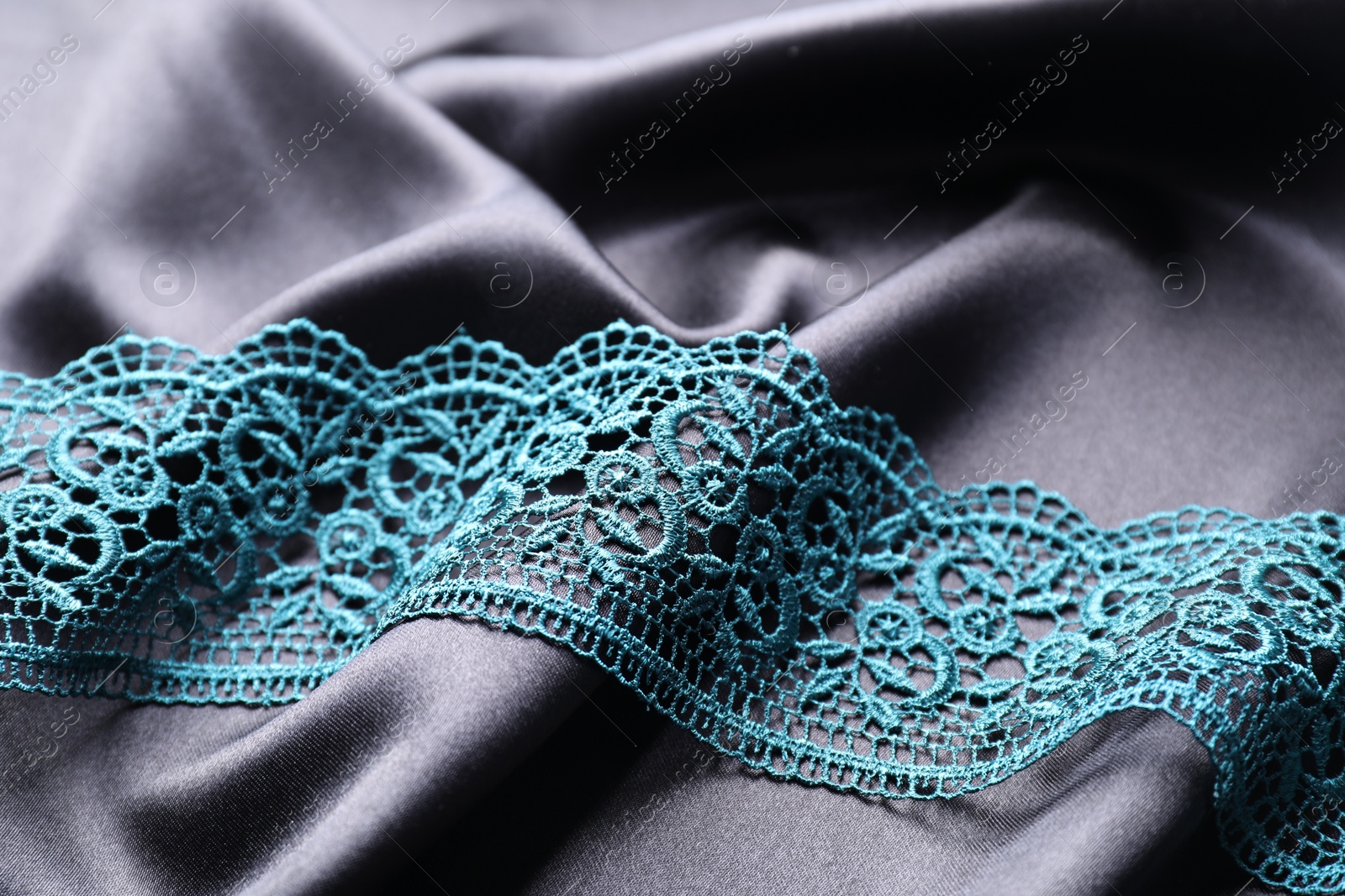 Photo of Beautiful green lace on black fabric, closeup