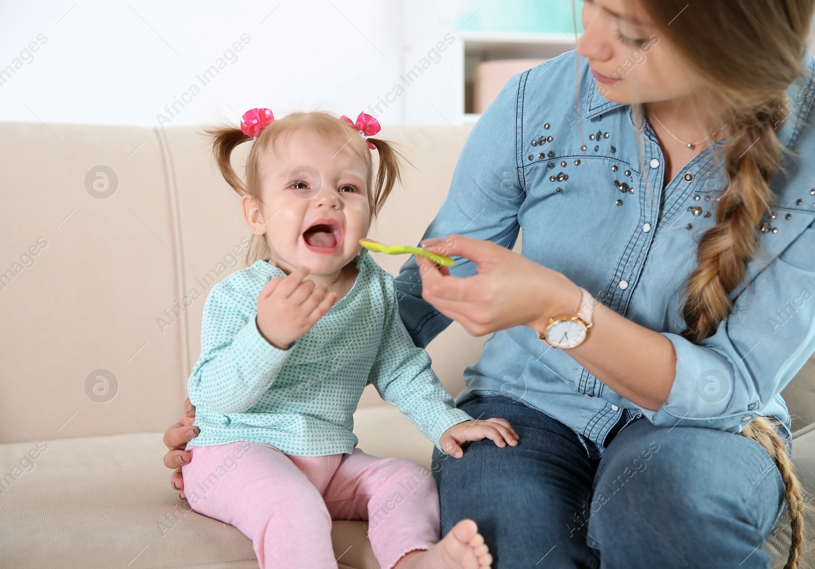 Photo of Caring mother feeding her cute little baby with healthy food at home