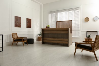 Photo of Stylish hotel lobby interior with wooden reception desk and armchairs