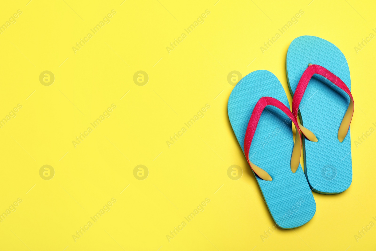 Photo of Stylish flip flops on yellow background, flat lay. Space for text