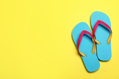 Photo of Stylish flip flops on yellow background, flat lay. Space for text