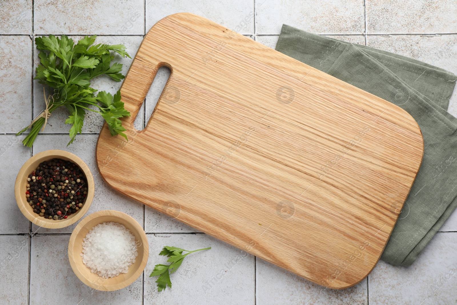 Photo of Cutting board, salt, pepper and parsley on white tiled table, flat lay. Space for text