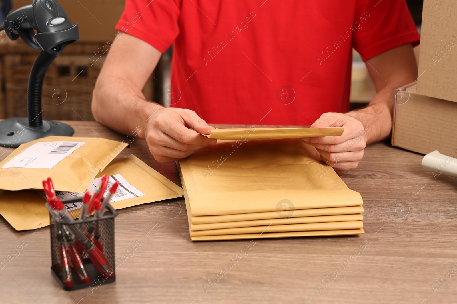 Photo of Post office worker with adhesive paper bags at counter indoors, closeup