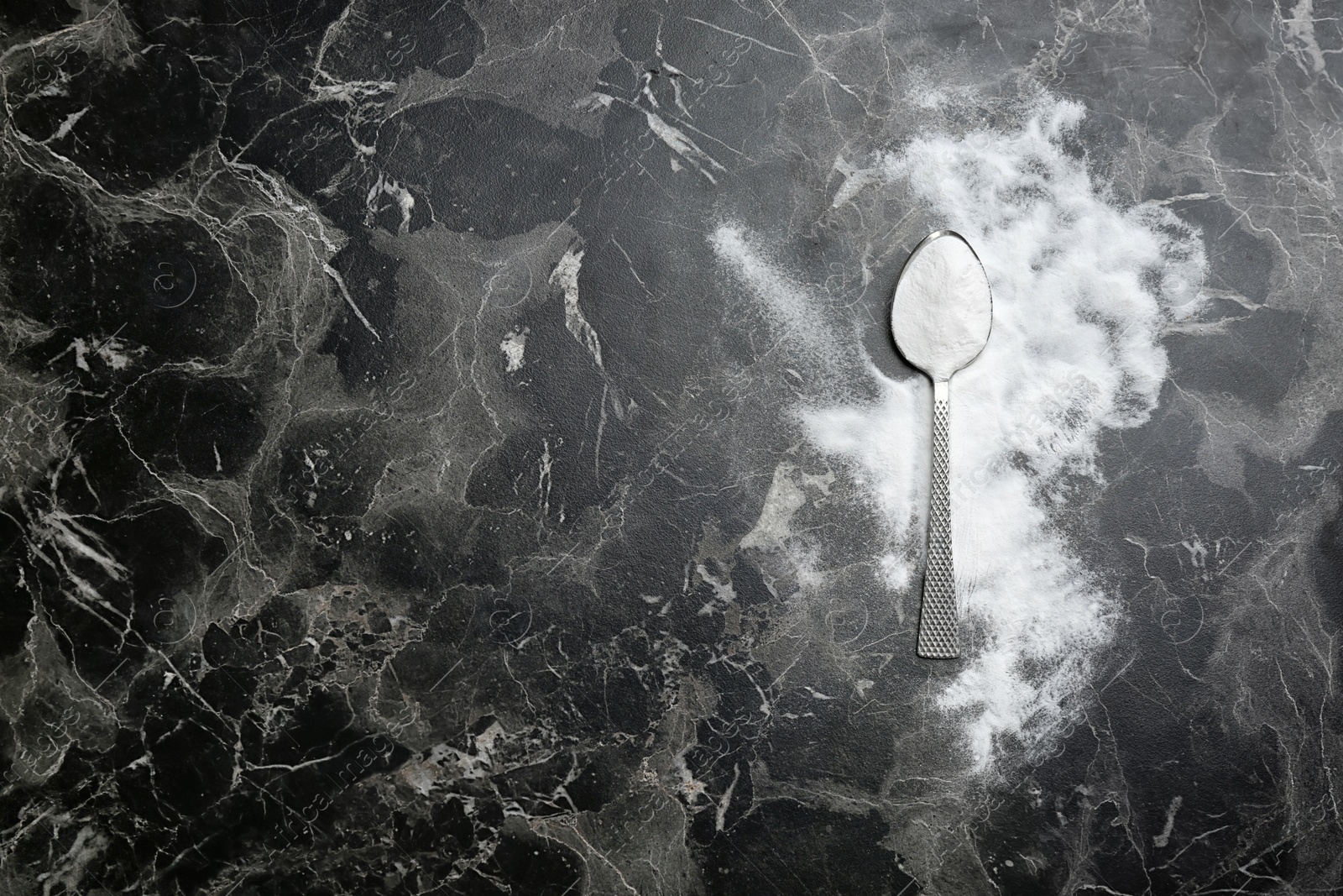 Photo of Spoon and baking soda on grey background, top view. Space for text