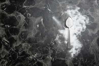 Spoon and baking soda on grey background, top view. Space for text