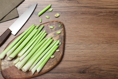 Photo of Flat lay composition with fresh lemongrass stalks on wooden table. Space for text