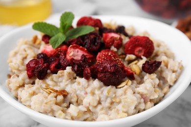 Photo of Oatmeal with freeze dried strawberries and mint on table, closeup