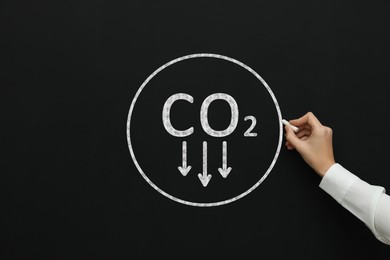 Image of Reduce carbon emissions. Woman drawing circle with chemical formula CO2 on blackboard, closeup