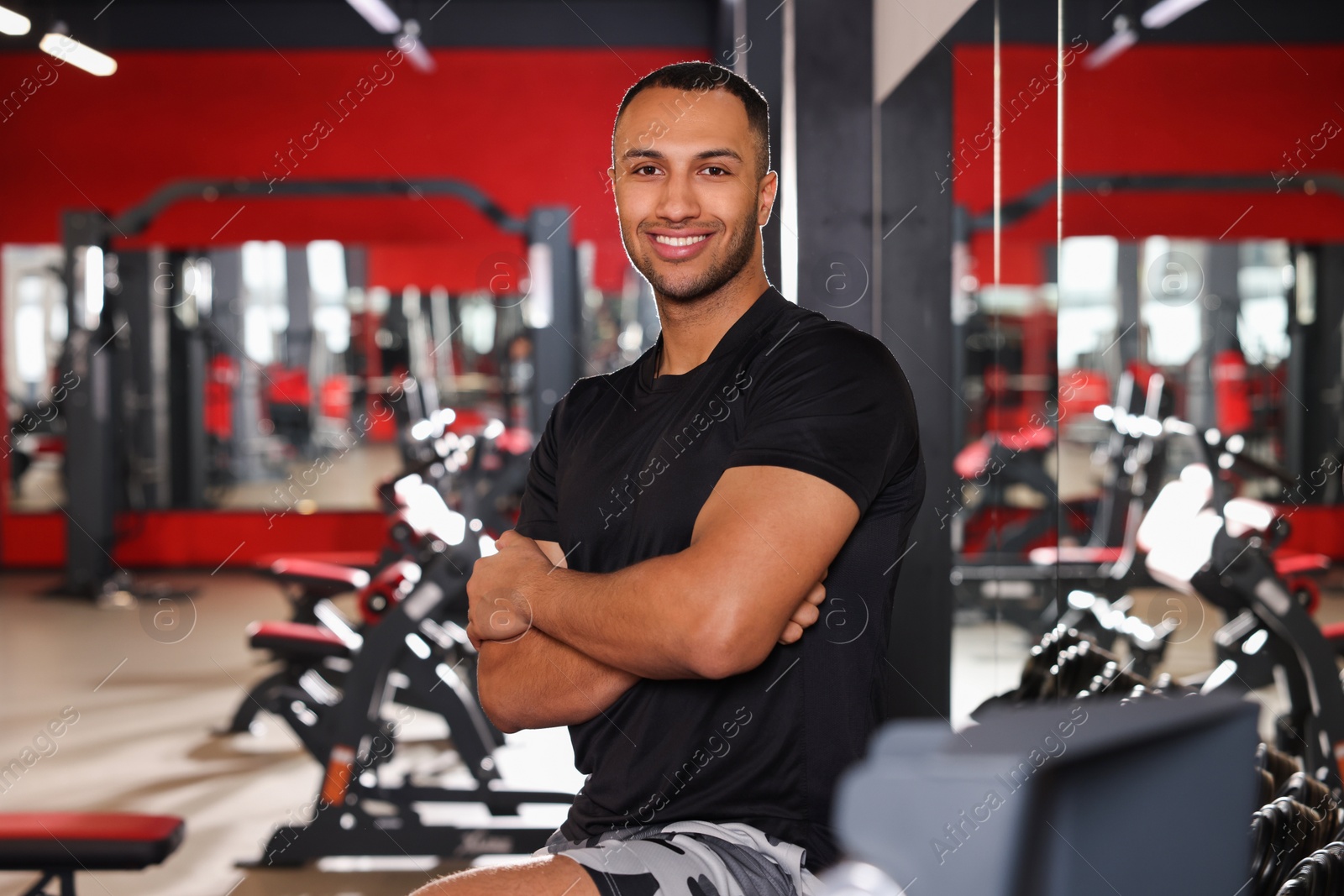 Photo of Happy trainer in modern gym, space for text