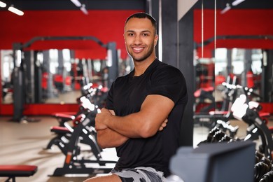 Happy trainer in modern gym, space for text