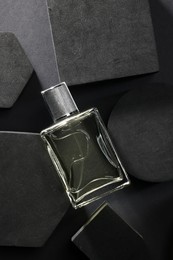 Photo of Stylish presentation of luxury men`s perfume in bottle on black background, top view