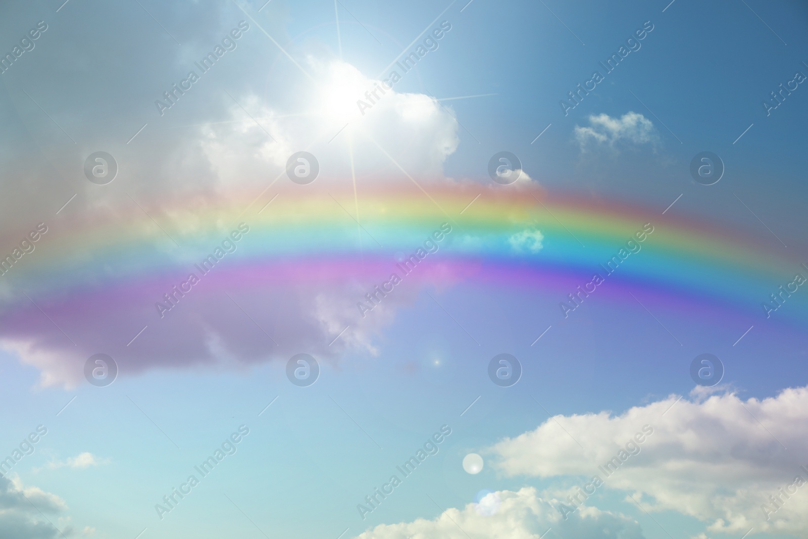 Image of Beautiful view of bright rainbow in blue sky on sunny day