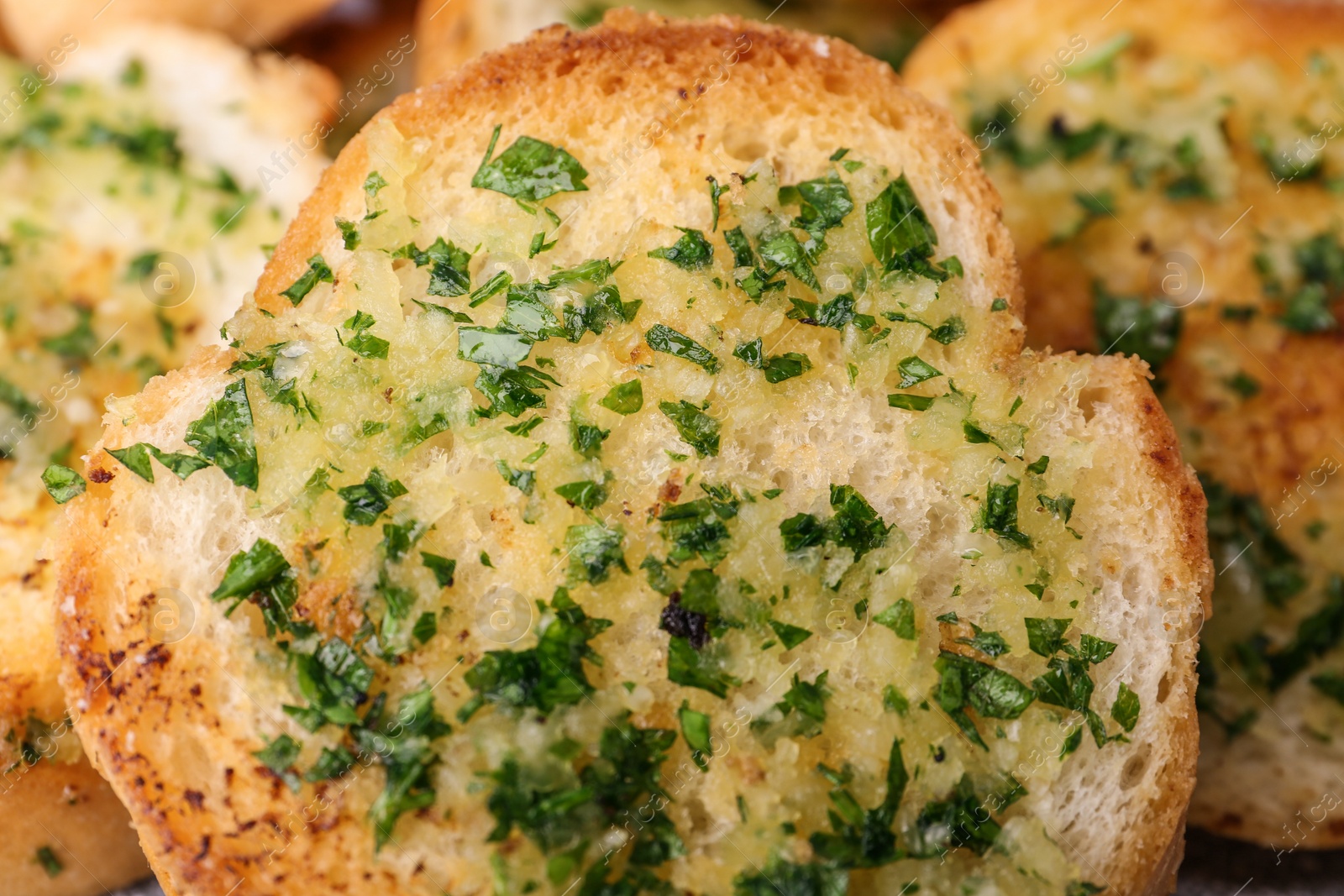 Photo of Slices of toasted bread with garlic and herbs as background, closeup