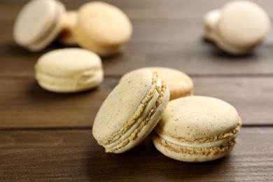 Photo of Delicious macarons on wooden table, closeup. Sweet dessert