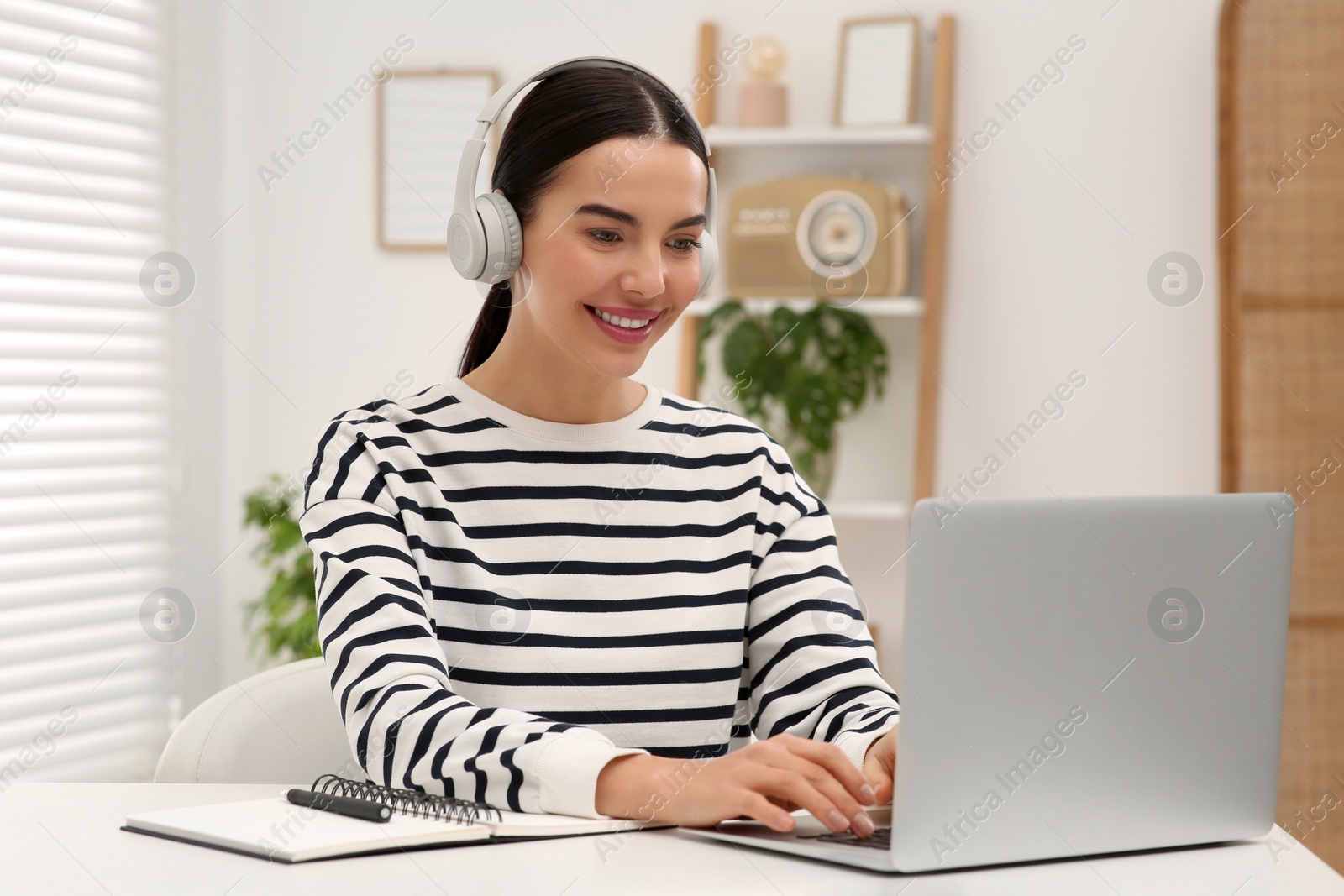 Photo of Online translation course. Student in headphones typing on laptop at home