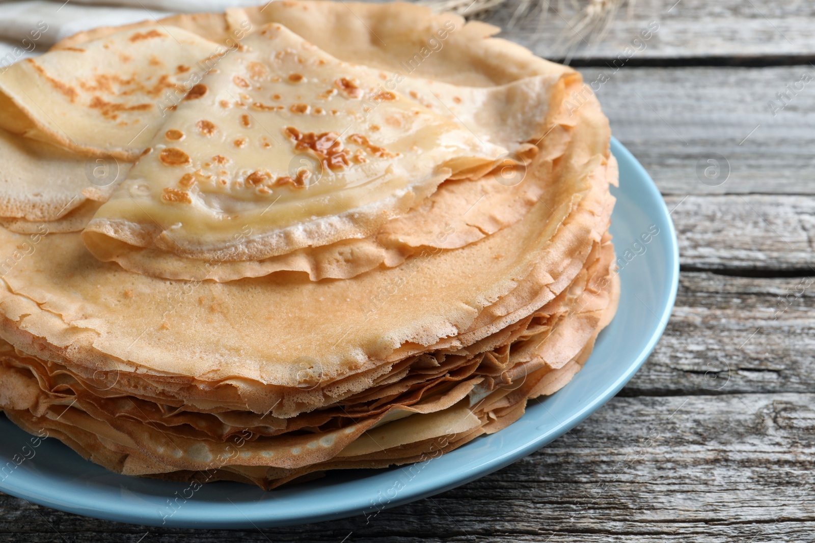 Photo of Stack of delicious crepes on wooden table, closeup